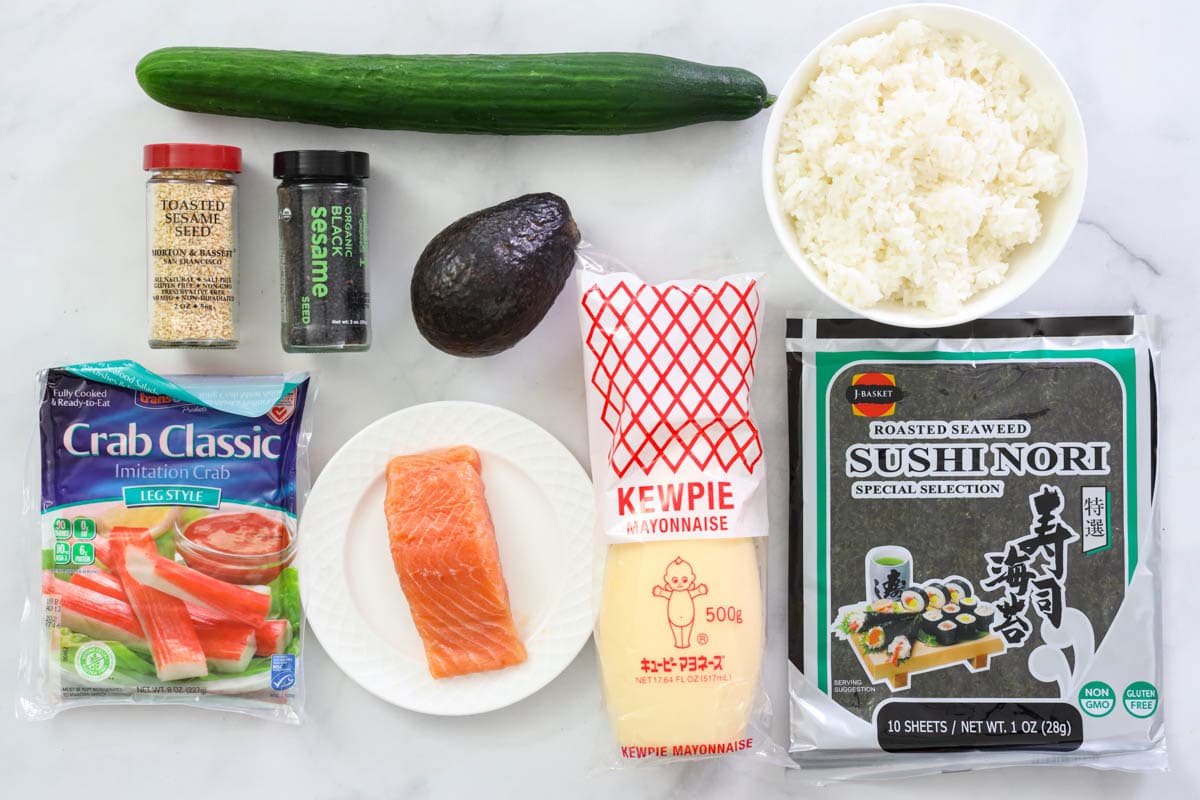 Ingredients for Spicy Salmon Roll: sushi nori, sushi rice, Japanese mayo, imitation crab, salmon, avocado, cucumber, toasted white sesame seeds, and black sesame seeds.