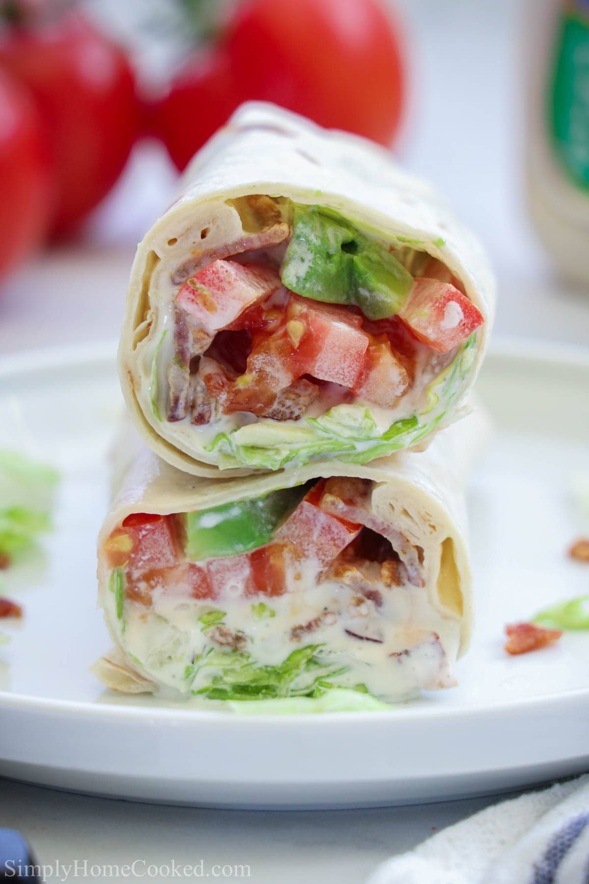 نصفان من Easy BLT Wrap مكدسان فوق بعضهما البعض على طبق أبيض.