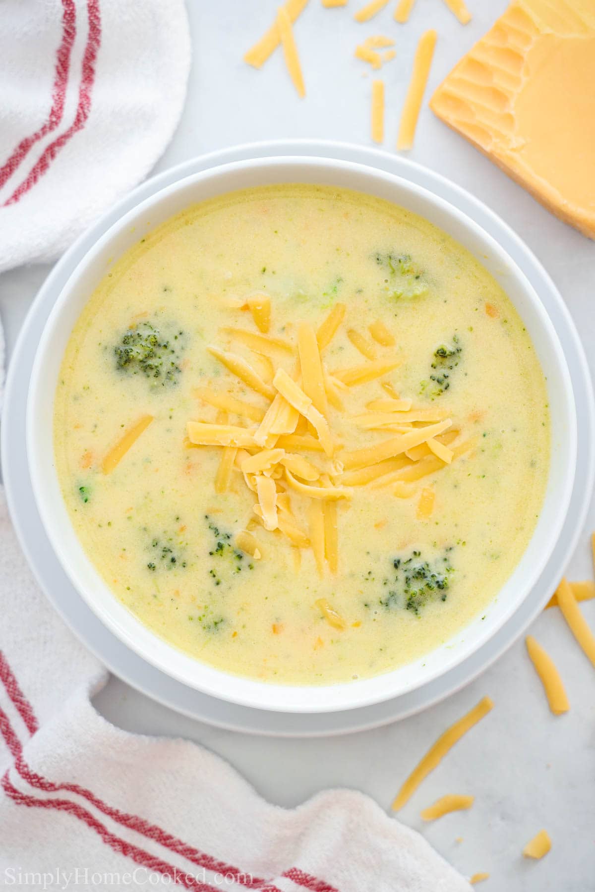 Overhead view of a bowl of Broccoli Cheddar Soup with shredded cheese on top.
