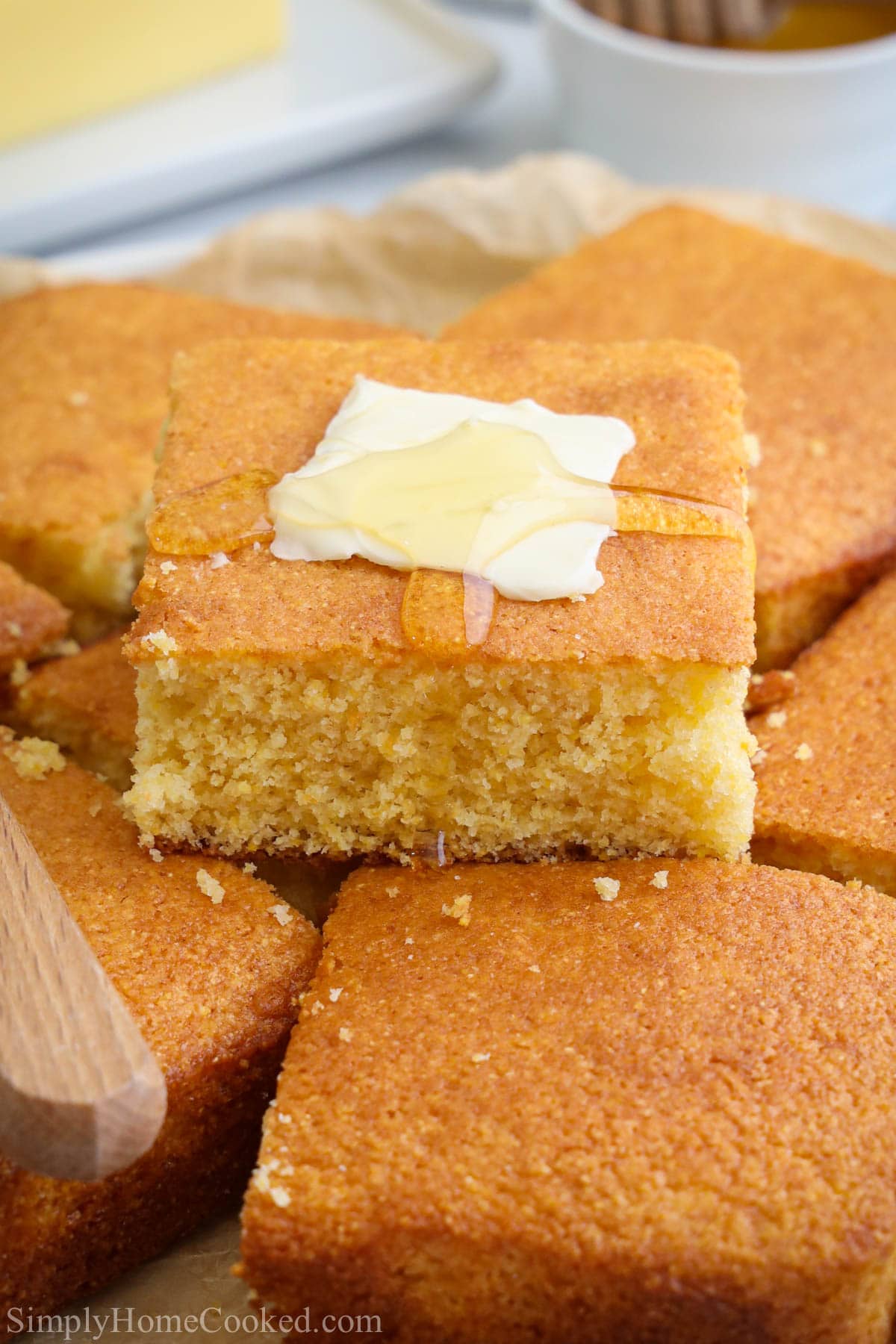 Stack of Buttermilk Cornbread squares with a pat of butter melting on one with honey.