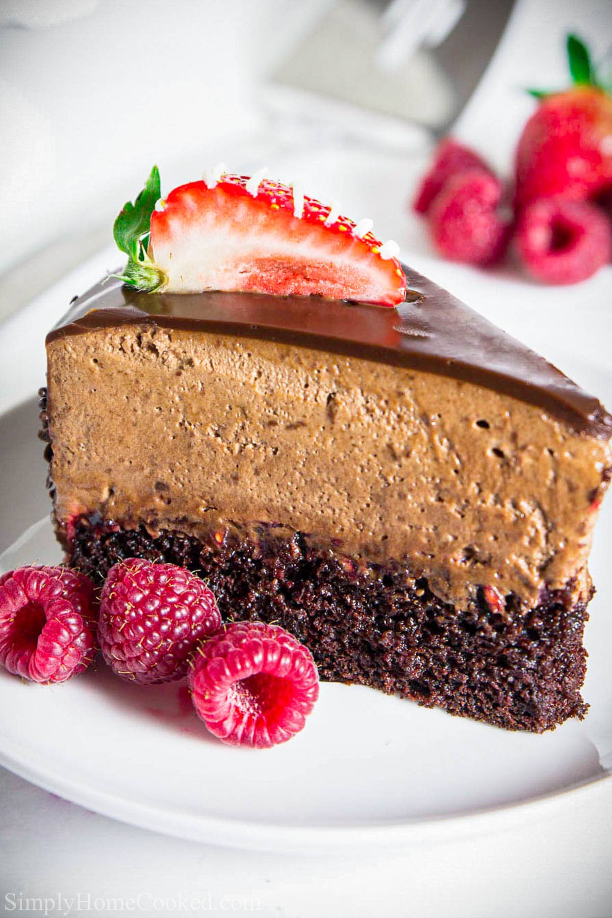 A slice of Chocolate Mousse Cake with berries on a white plate.