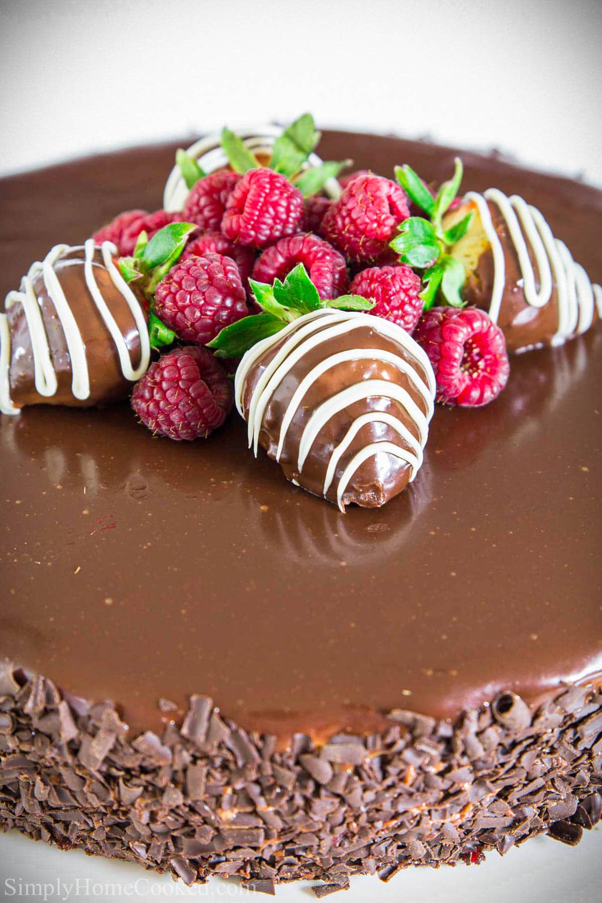 Chocolate Mousse Cake with chocolate shavings on the side and strawberries and raspberries on top.