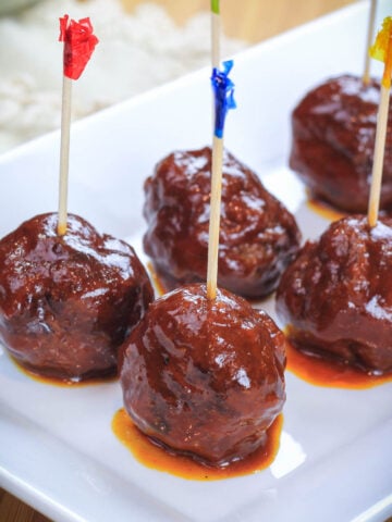 Grilled BBQ Meatballs with toothpicks in them on a white plate.