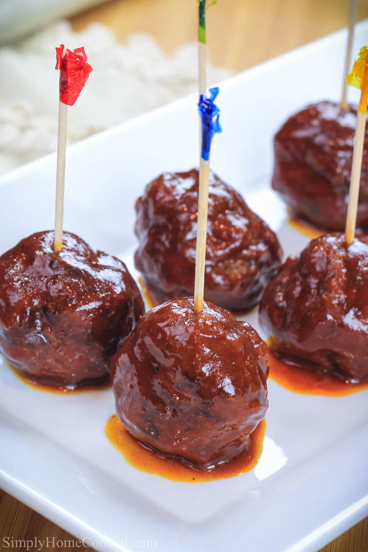 Grilled BBQ Meatballs with toothpicks in them on a white plate.