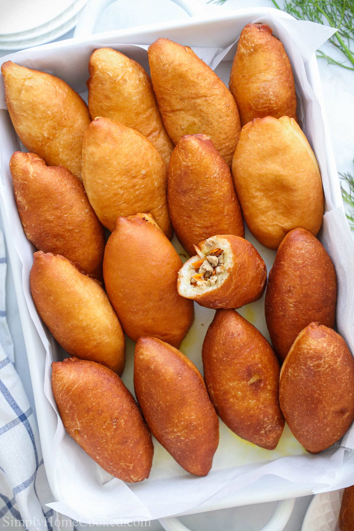 Piroshki lined up in a container with one missing a bite