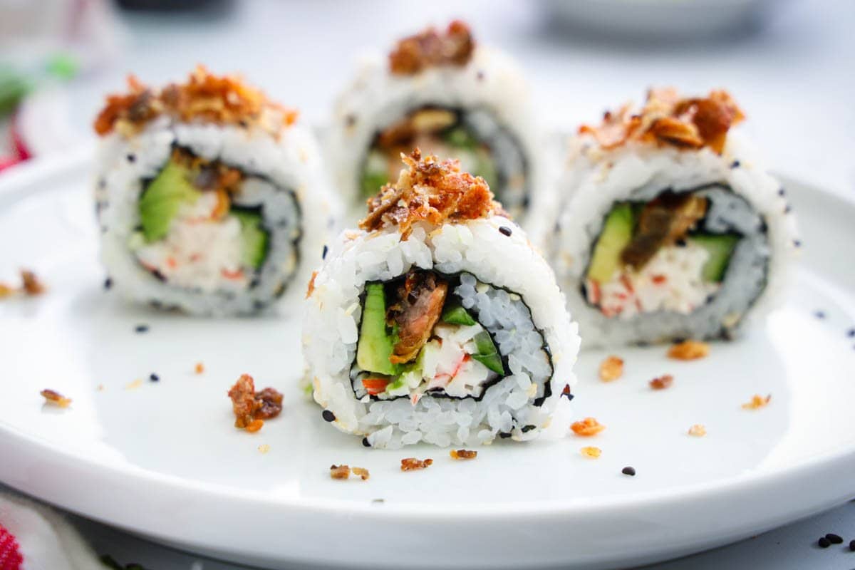 Salmon Skin Roll cut on a white plate with crispy salmon skins on top.