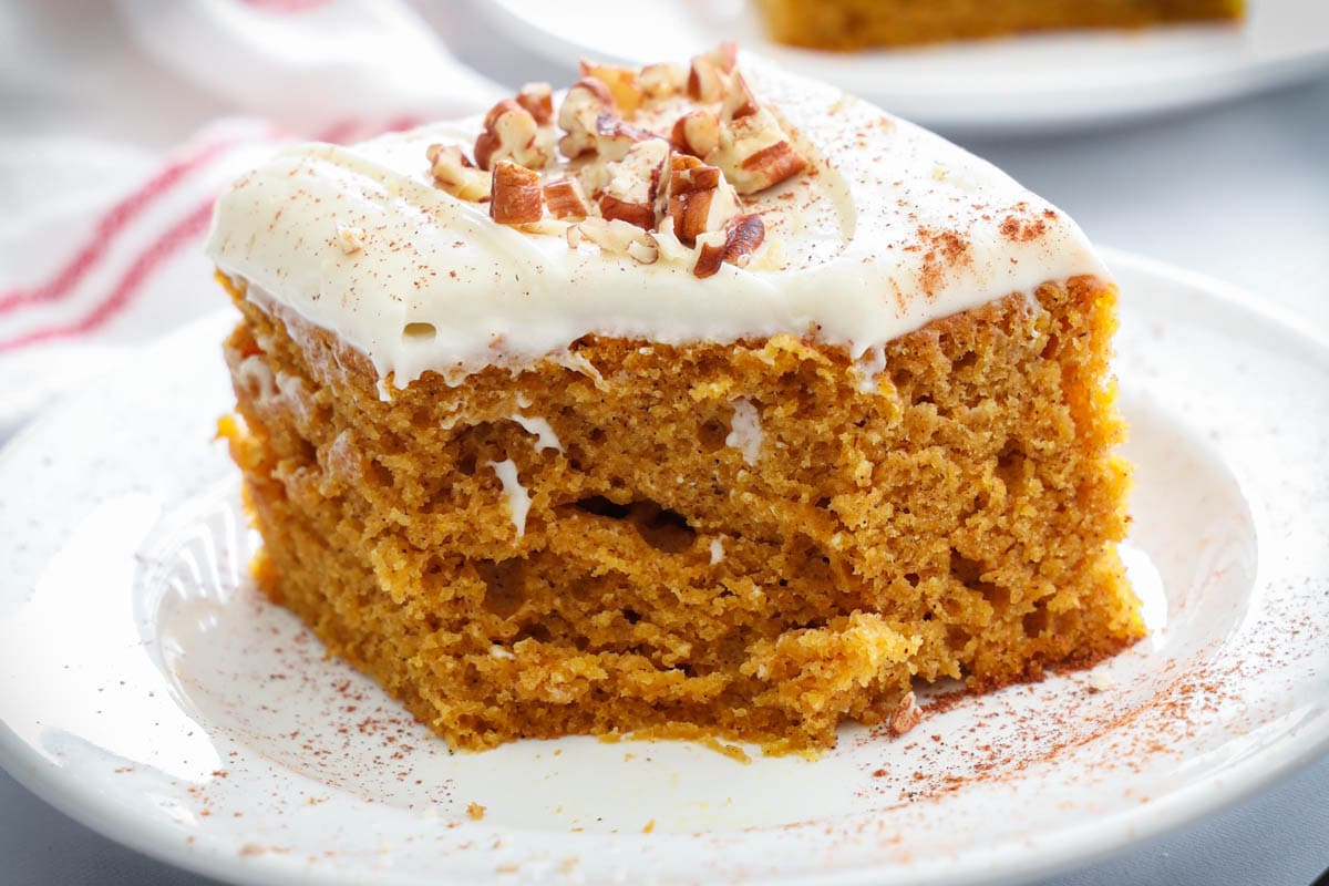 Slice of Pumpkin Cake on a white plate with a bite missing.