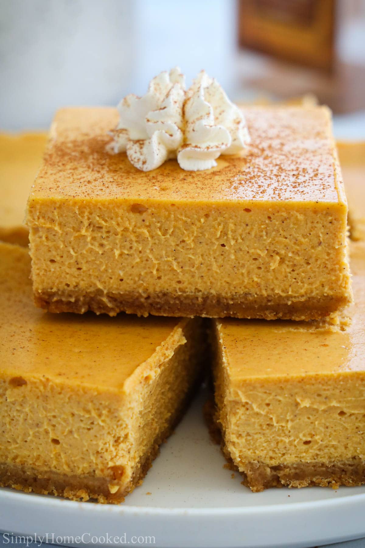 Pumpkin Cheesecke Bars stacked up adn topped with whipped cream.