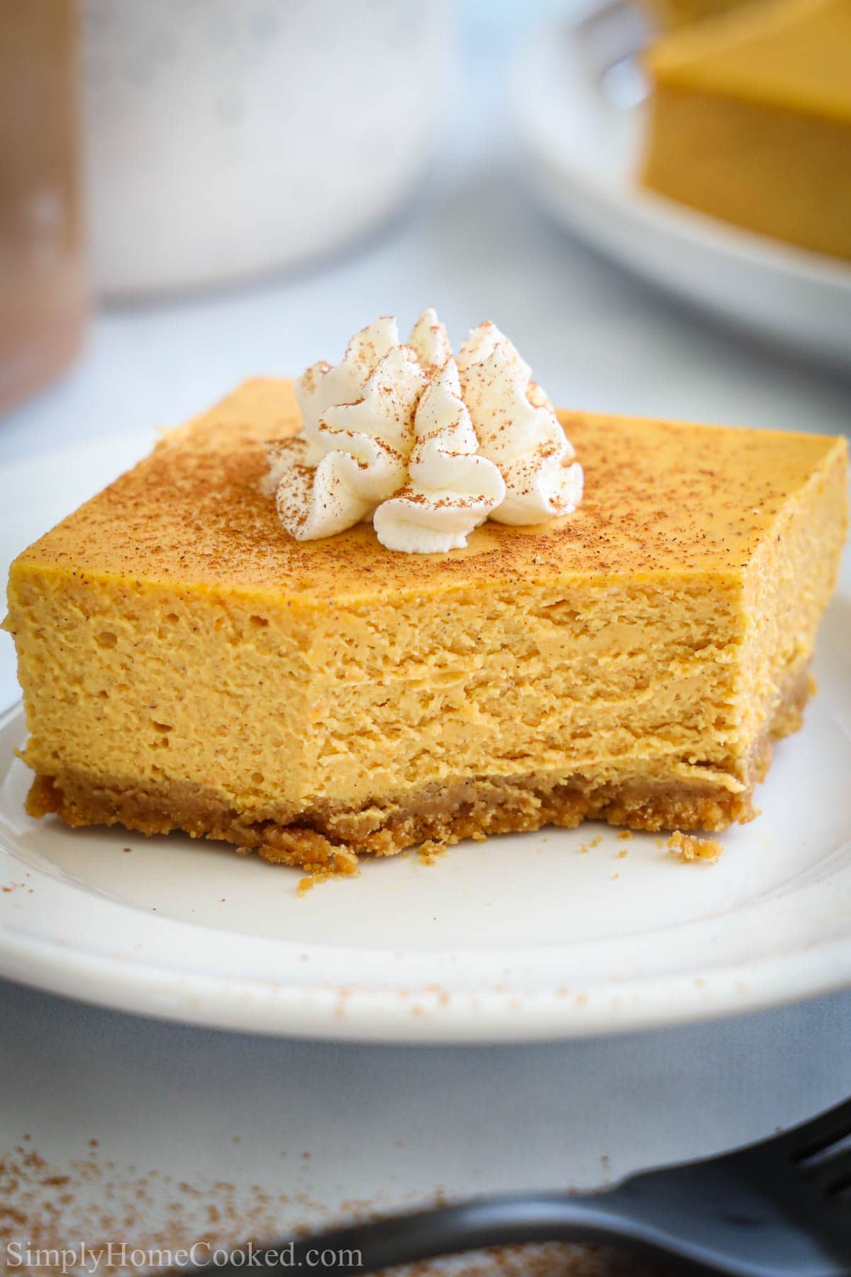 Slicce of Pumpkin Cheesecake Bar on a white plate missing a bite