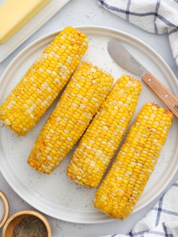 Plate of Air Fryer Corn on the Cob with a knife and butter nearby.