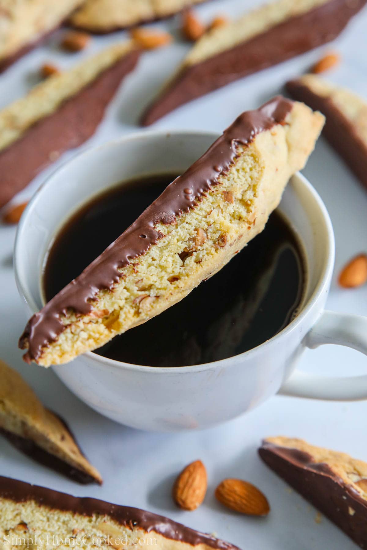 Chocolate Dipped Almond Biscotti laying on top of a cup of coffee.