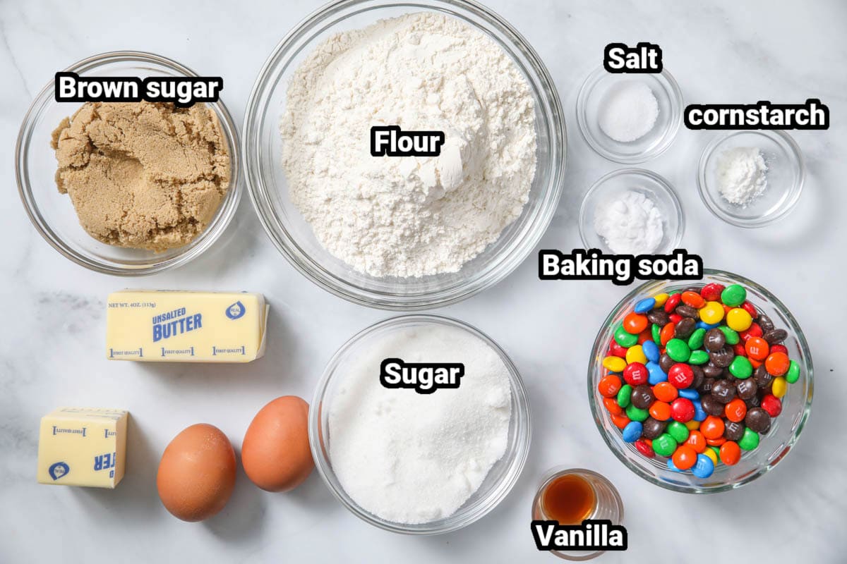 Ingredients for Chewy M&M Cookies: flour, brown sugar, white sugar, butter, eggs, salt, cornstarch, vanilla, baking soda, and M&Ms.