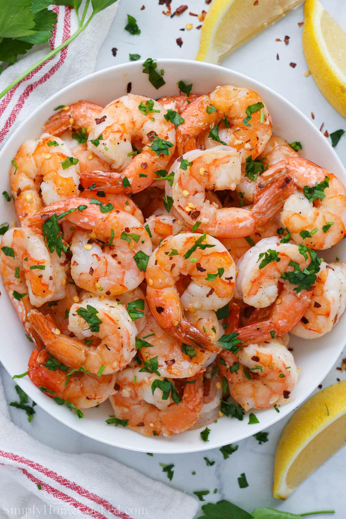 Plate of Baked Shrimp with lemon wedges and garnished with parsley.