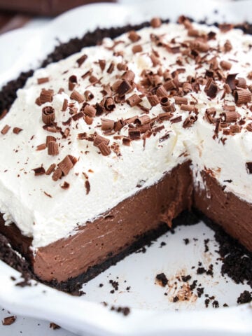 Luscious Chocolate Cream Pie adorned with whipped cream and chocolate shavings, with a slice artfully removed.