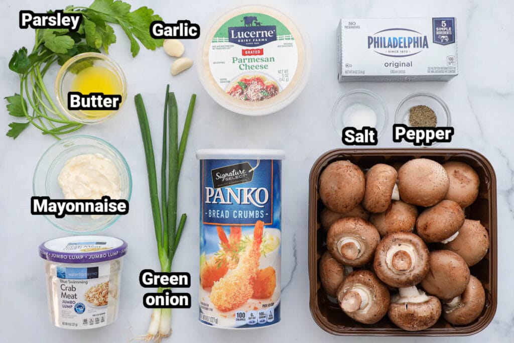 Ingredients for Crab Stuffed Mushrooms, including parsley, butter, garlic, Parmesan cheese, cream cheese, salt, pepper, Panko, green onions, mayo, crab meat, and mushrooms.