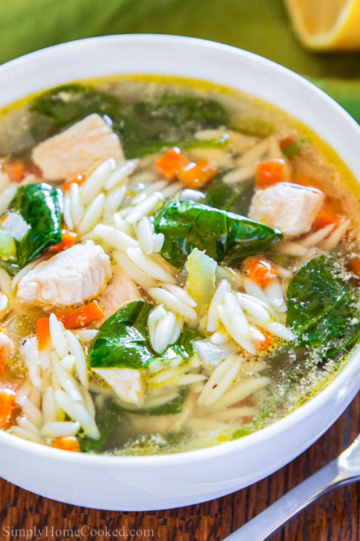 Bowl of Lemon Chicken Orzo Soup with orzo, spinach, chicken, and broth.