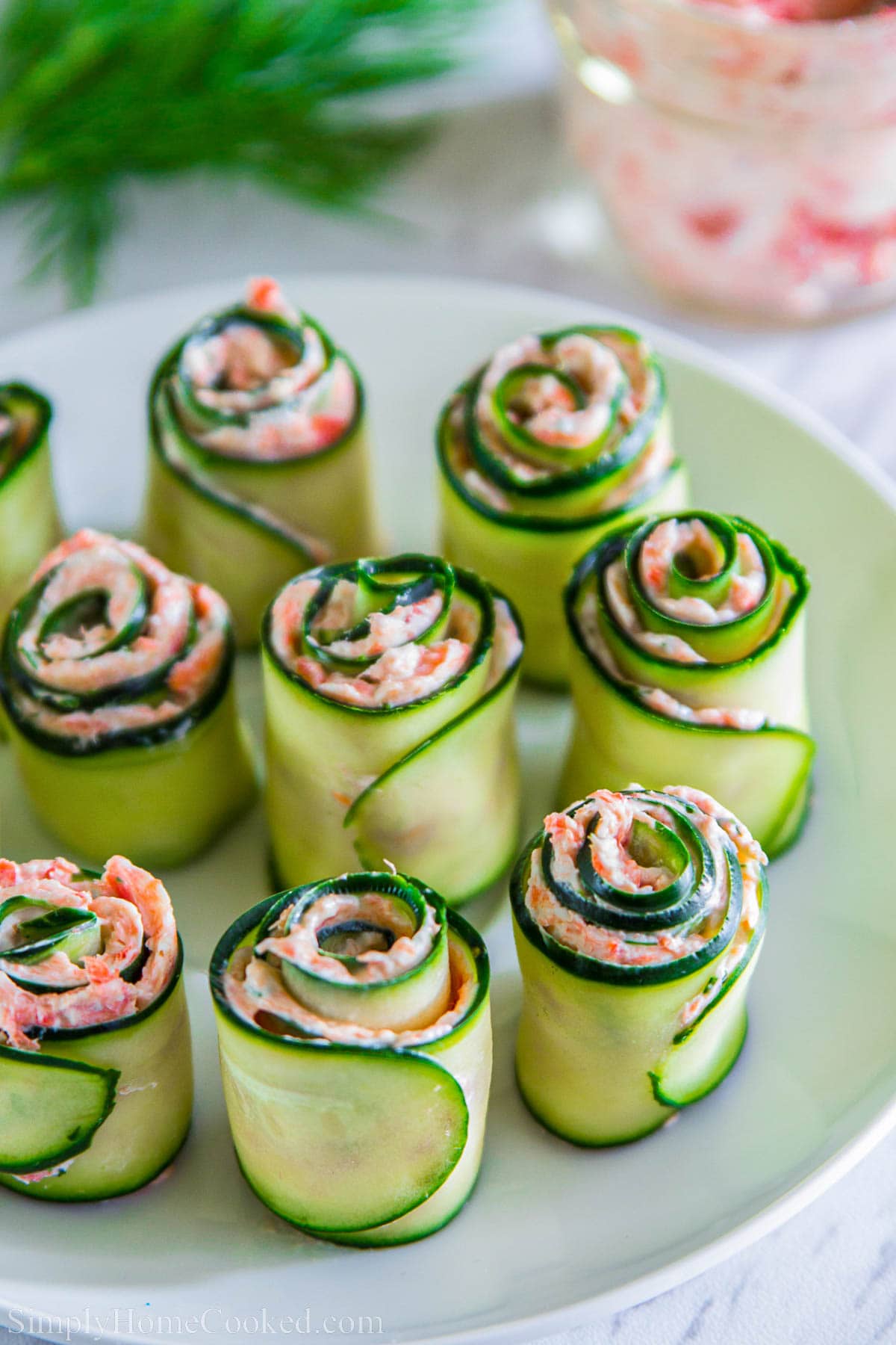 Plate of Smoked Salmon Appetizers made with rolled cucumber slices, salmon, cream cheese, and dill.