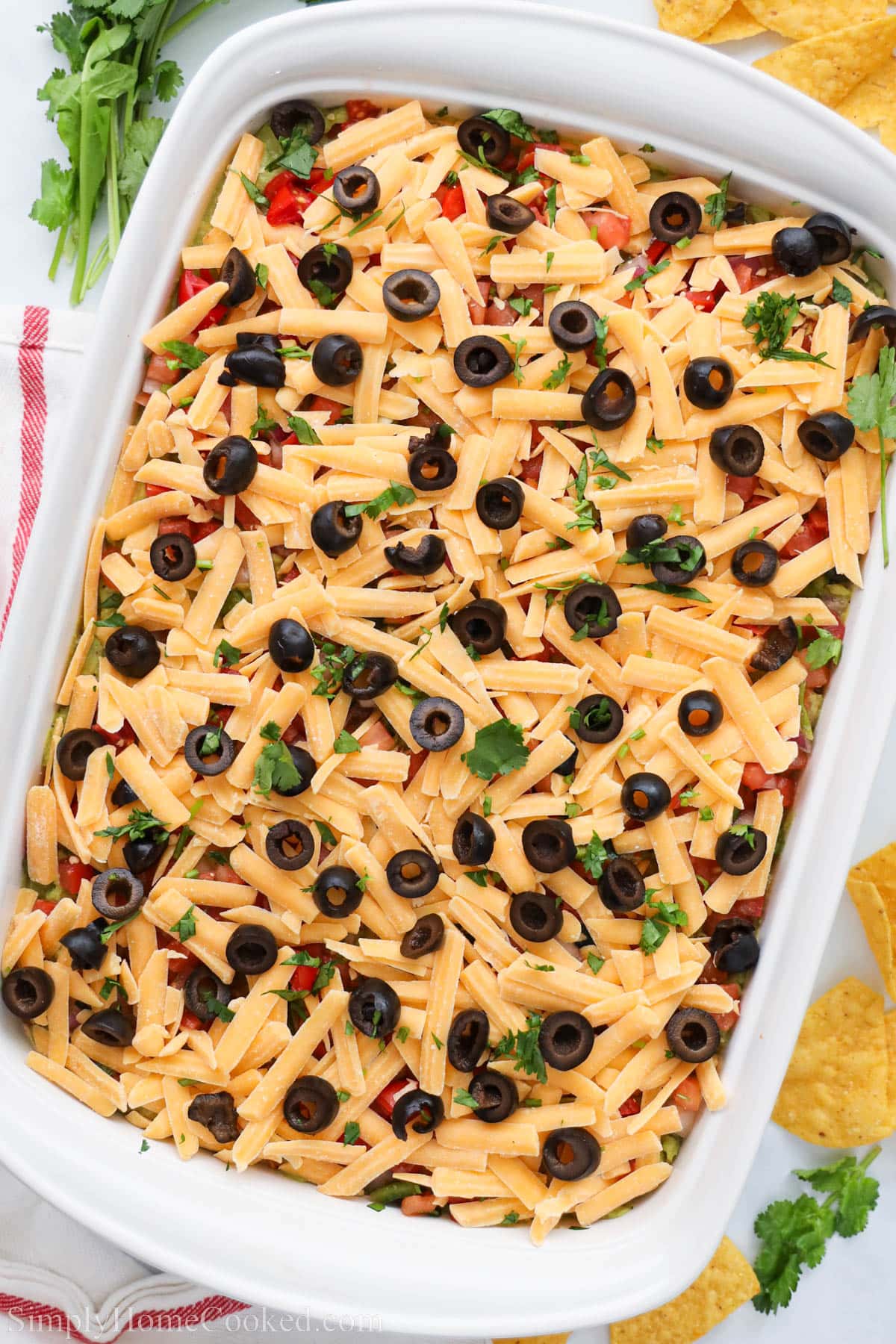 Baking dish of 7 Layer Taco Dip topped with cilantro and black olives.