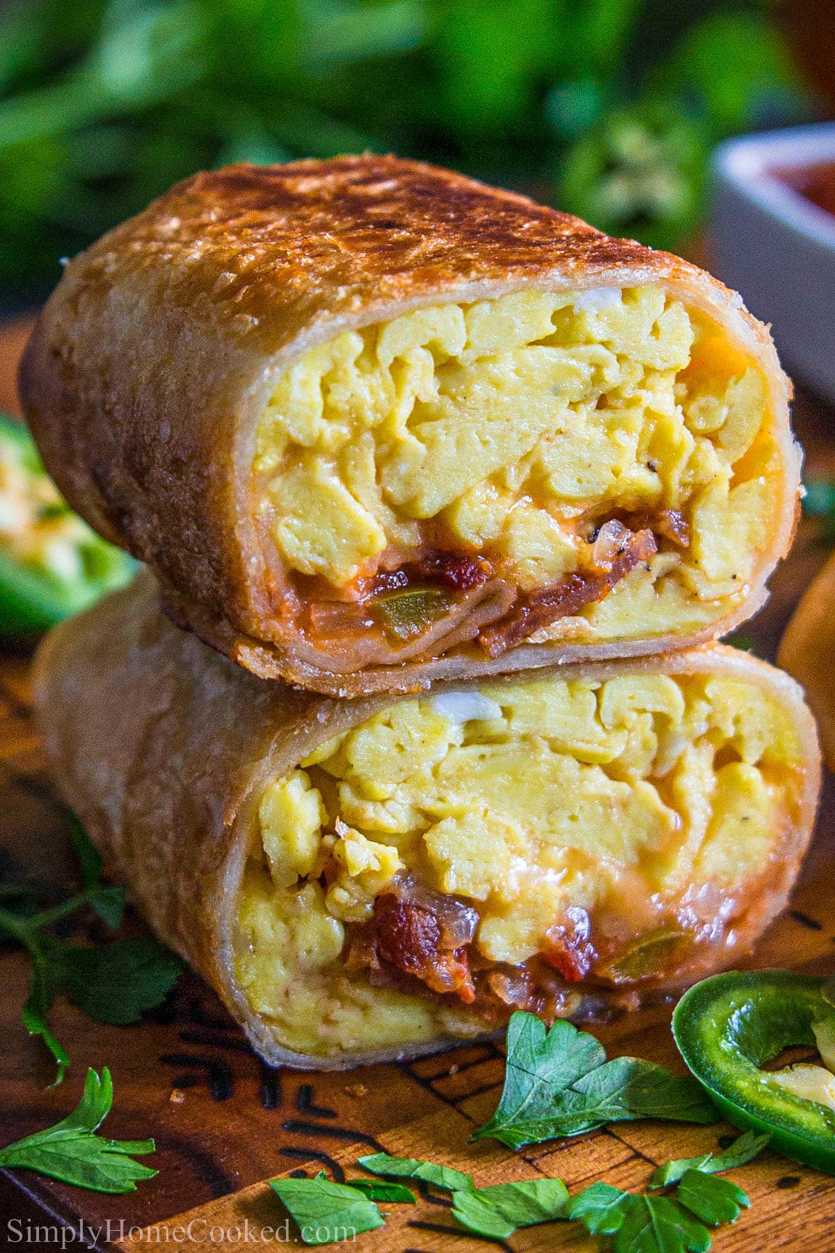 Breakfast Burritos with eggs, bacon, cheesy, and salsa cut in half and stacked.
