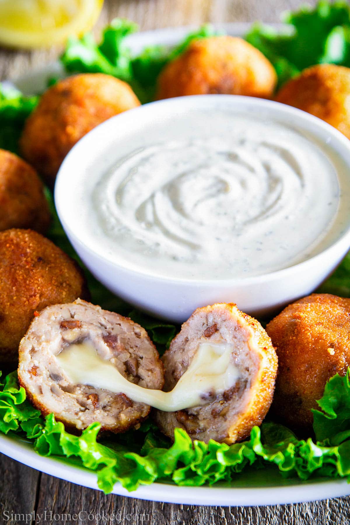 Chicken Croquettes around a bowl of ranch dressing, one split in half to show off the gooey cheese.