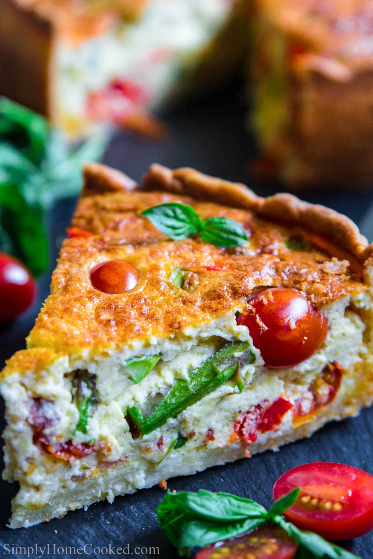 Slice of Quiche Lorraine with asparagus and cherry tomatoes.