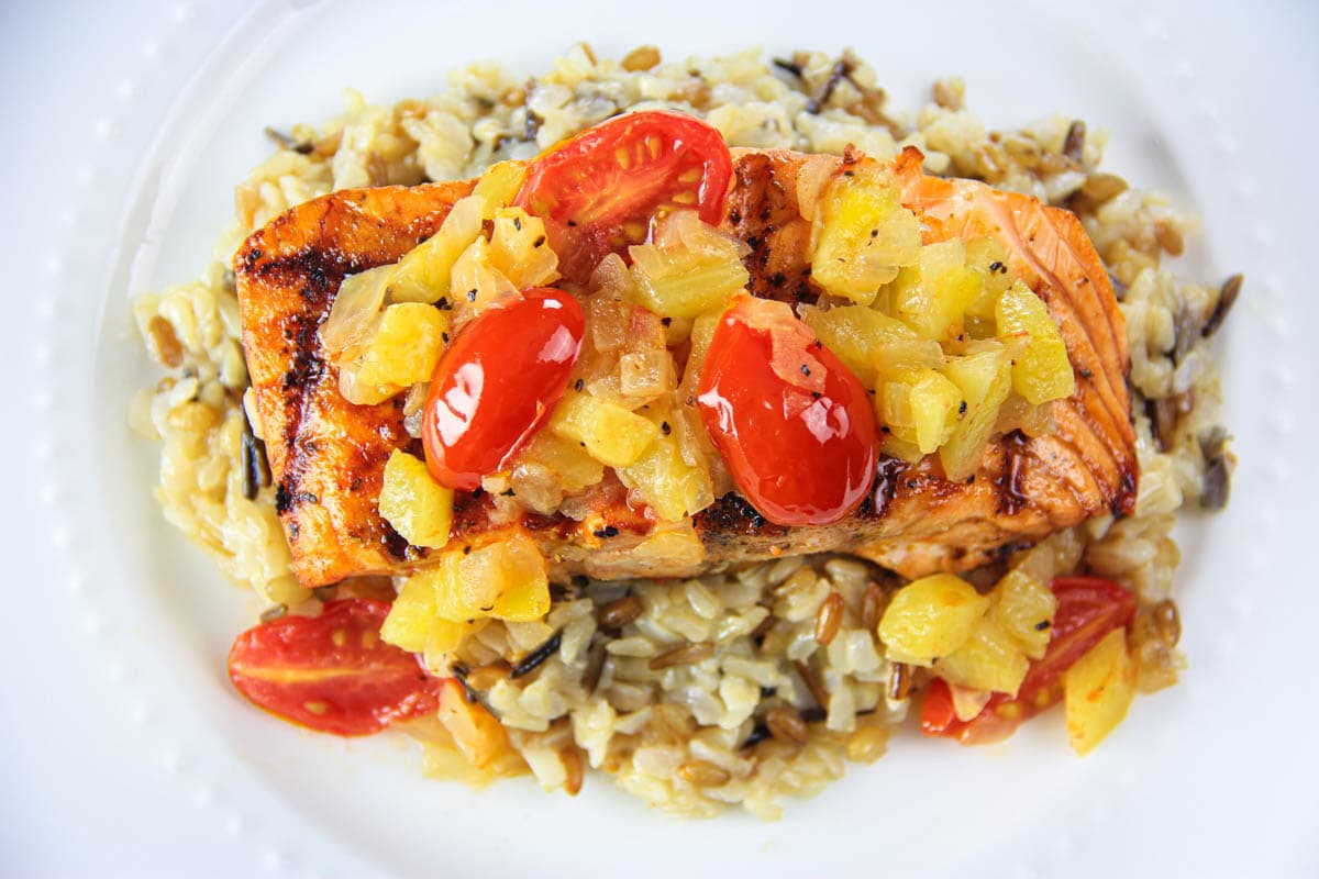 Pineapple Salmo topped with pineapple and cherry tomatoes on a bed of wild rice.