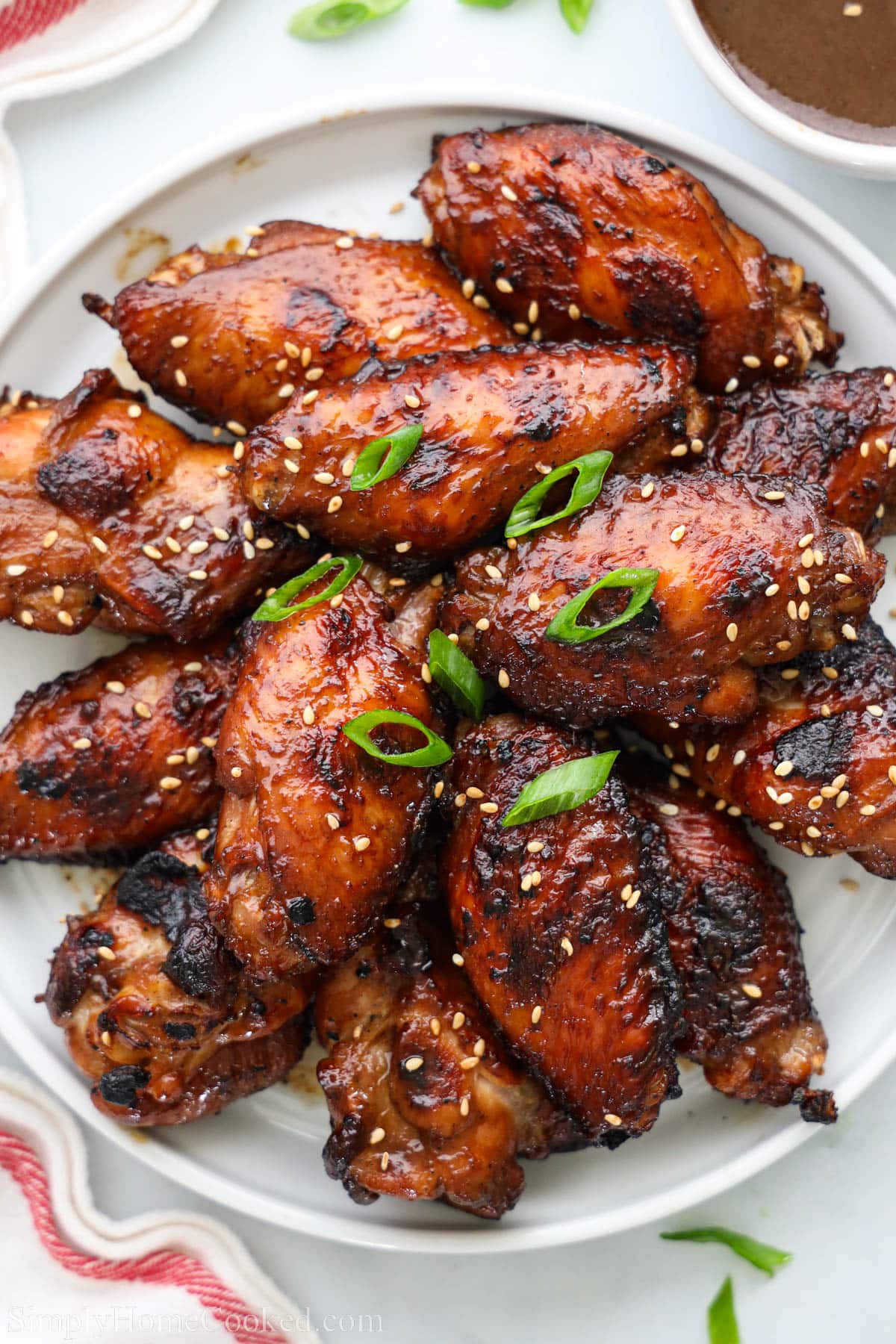 Teriyaki Chicken Wings garnished with sesame seeds and green onion on a white plate.