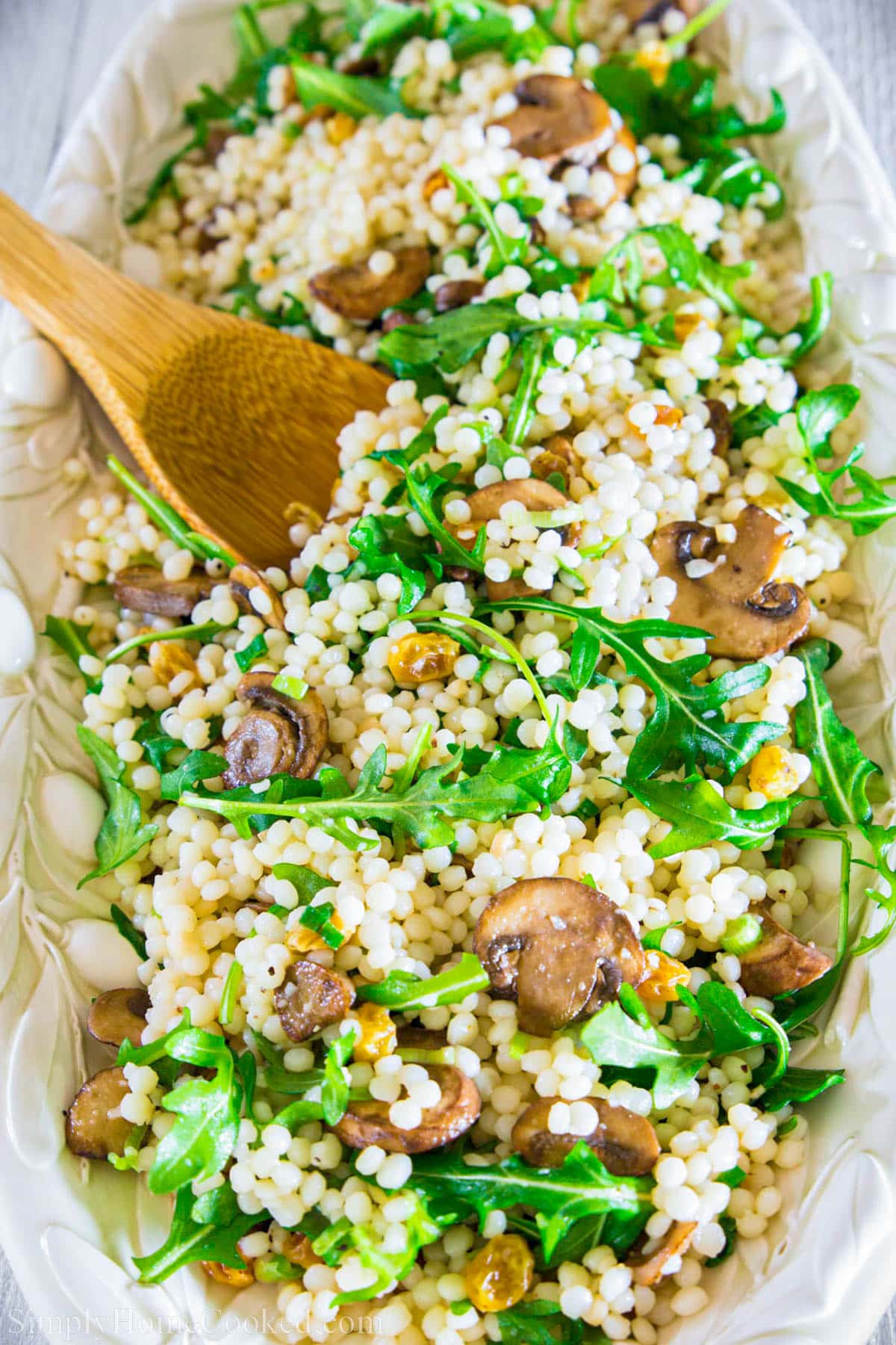 Couscous Arugula Salad and a wooden spoon.