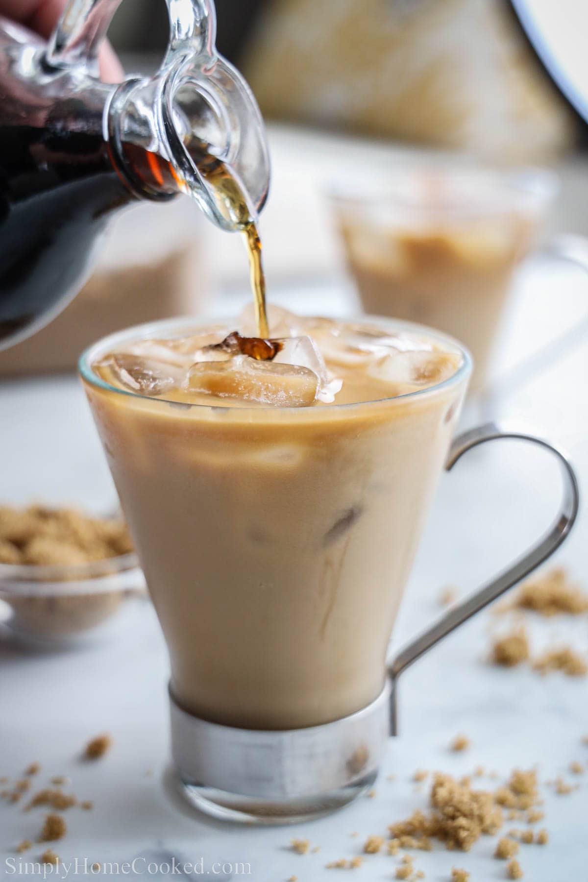 Brown Sugar Syrup in a cruet being drizzled into an iced coffee in a cup.