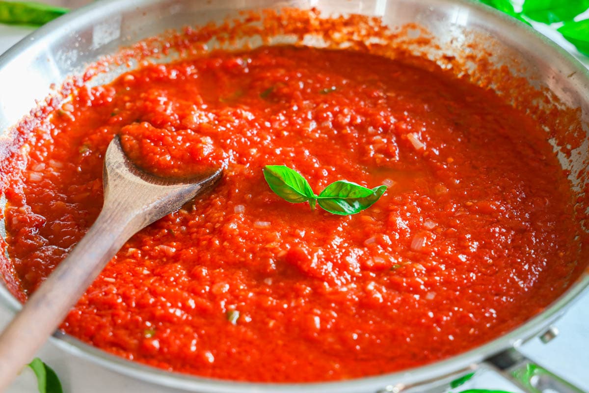 Pomodoro Sauce in a pan with basil and wooden spoon.