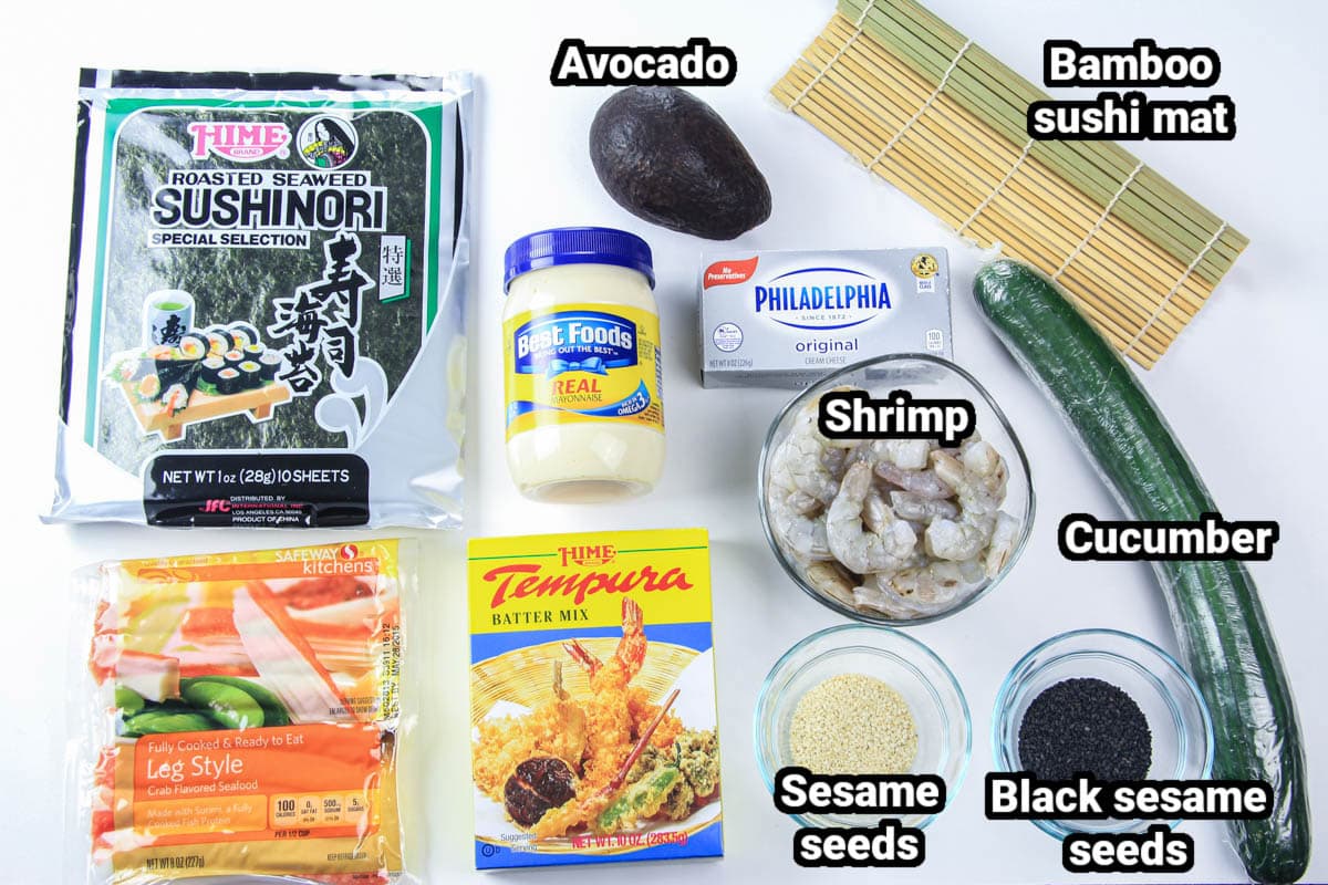 Ingredients for a tempura shrimp roll: nori sushi, avocado, bamboo sushi mat, imitation crab, tempura batter mix, mayo, cream cheese, shrimp, cucumber and white and black sesame.