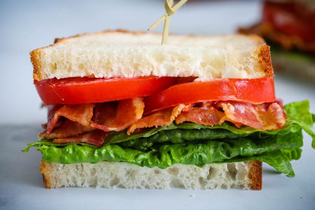Half a BLT Sandwich with a toothpick in the center holding the bacon, lettuce, and tomato in place.