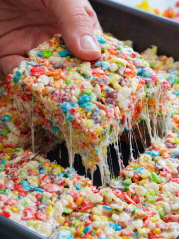 Fruity Pebbles Treats in a pan with one square being lifted out.