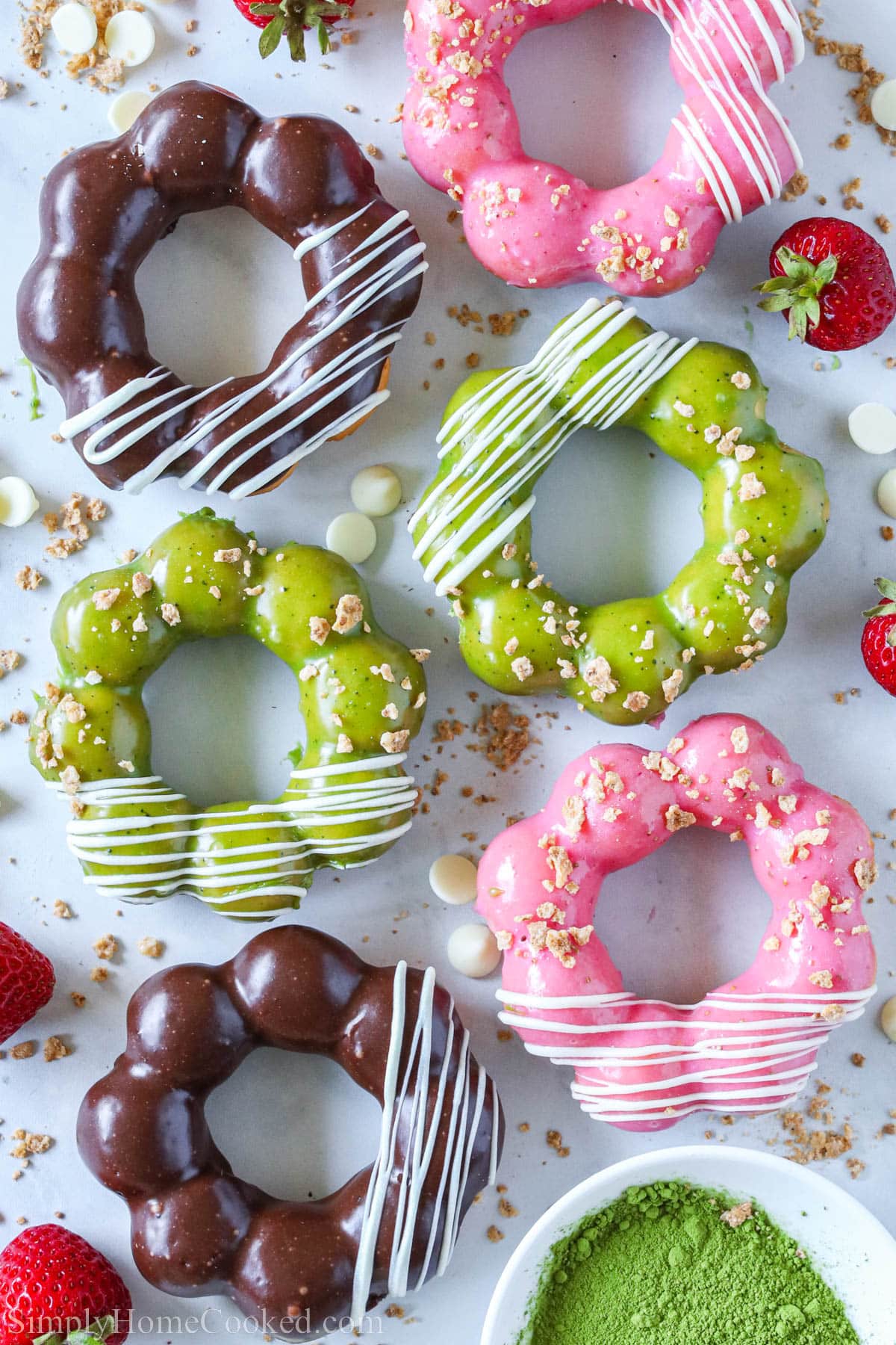 Mochi Donuts covered in matcha glaze, Nutella glaze, and strawberry glaze, then drizzled with white chocolate.