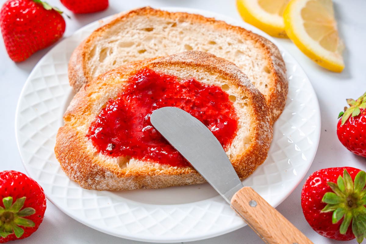 3-ingredient Strawberry Jam being spread with a knife over bread.