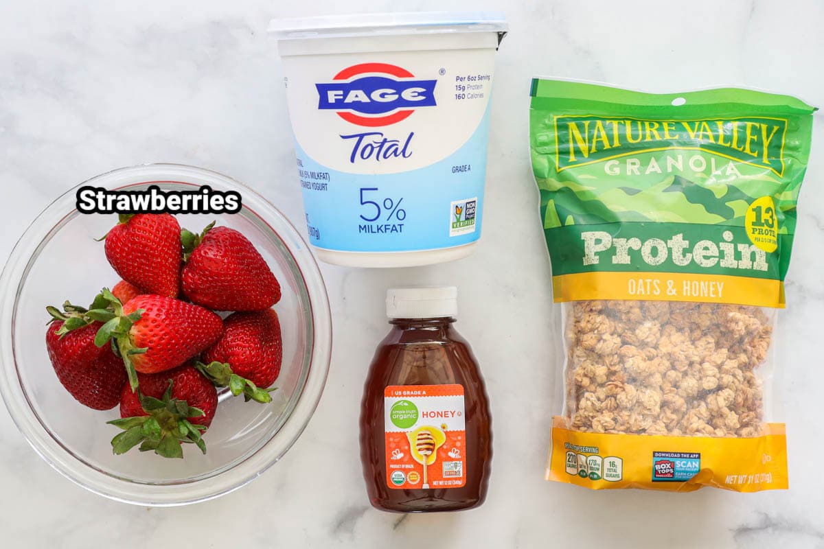 Ingredients for a strawberry parfait: strawberries, yoghurt, honey and muesli.