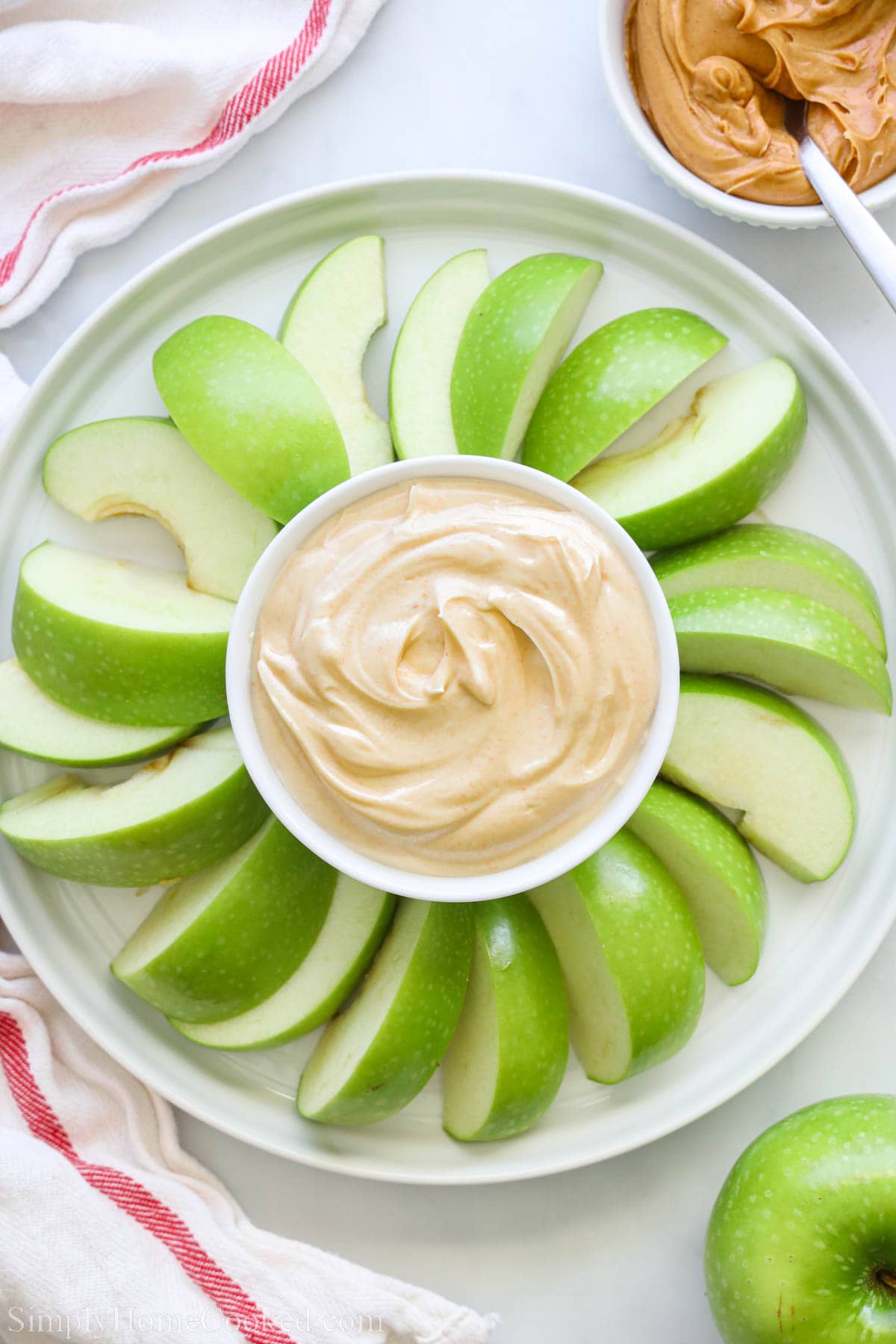 Peanut Butter Yogurt Dip in the center of apple slices with peanut butter nearby.