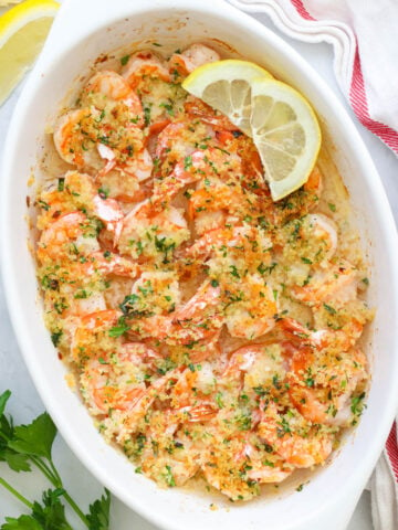Baked Shrimp Scampi in a casserole dish with lemon slices on top.