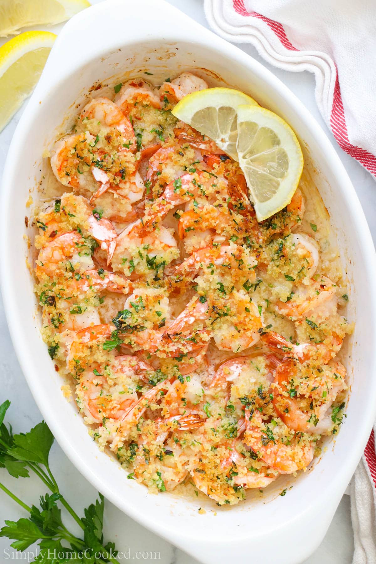 Baked Shrimp Scampi in a casserole dish with lemon slices on top.