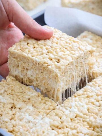 Brown Butter Rice Krispie Treats cut in a pan, one being lifted out.