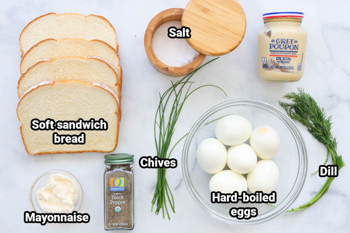 Egg Sandwich ingredients: soft sandwich bread, salt, Dijon mustard, mayonnaise, chives, hard boiled eggs, dill, and black pepper.