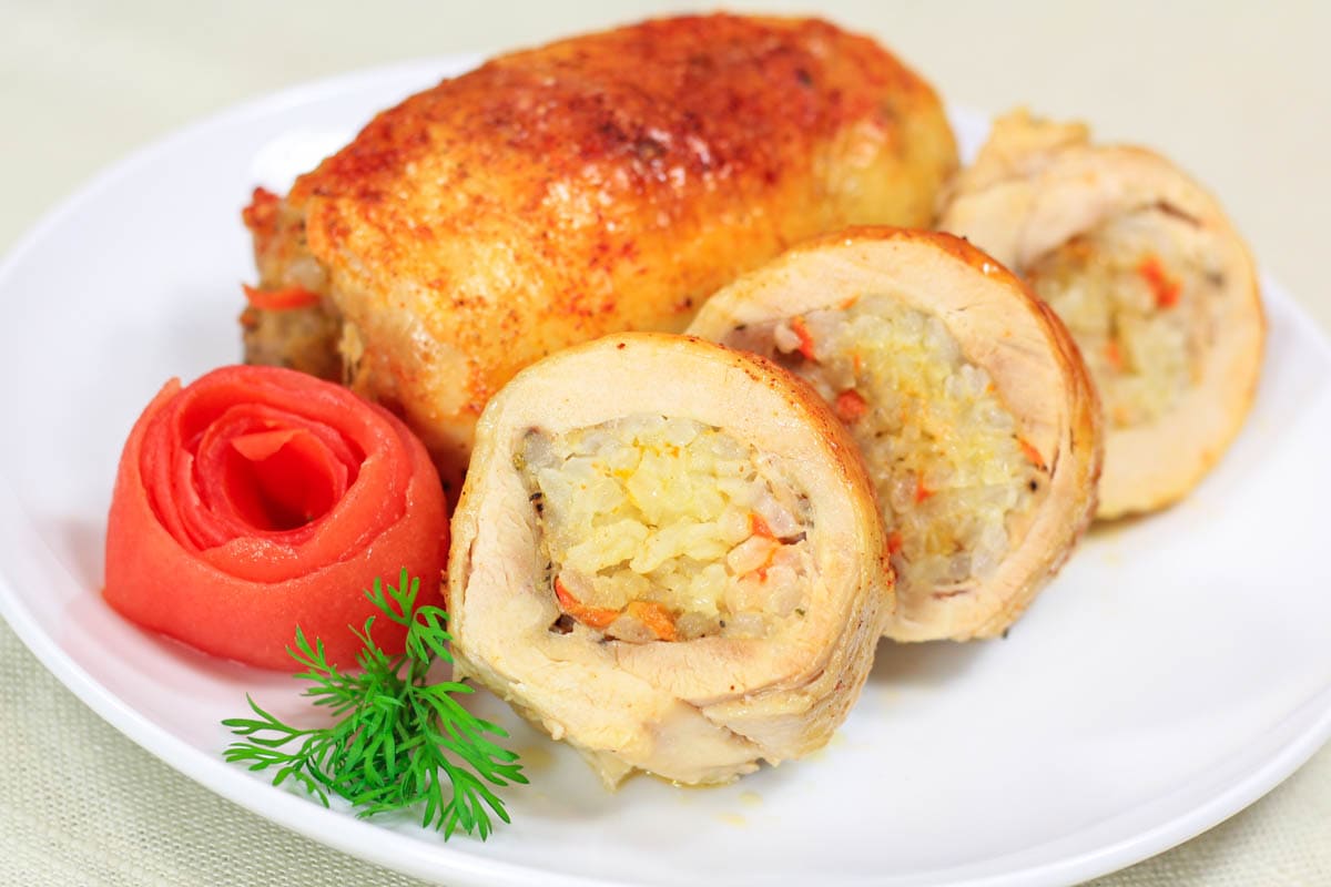 Rice Stuffed Chicken Thighs on a plate with some slices, carrot, and parsley.