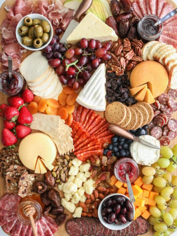 Ultimate Charcuterie Board with meats, cheese, nuts, fruits, spreads, and crackers.