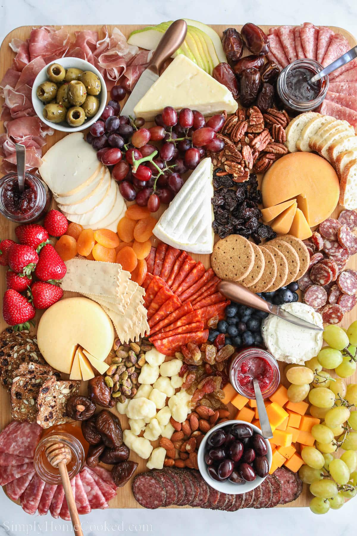 Ultimate Charcuterie Board with meats, cheese, nuts, fruits, spreads, and crackers.