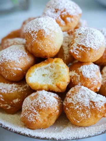 Close up of Zeppoles on a plate with powdered sugar on top.