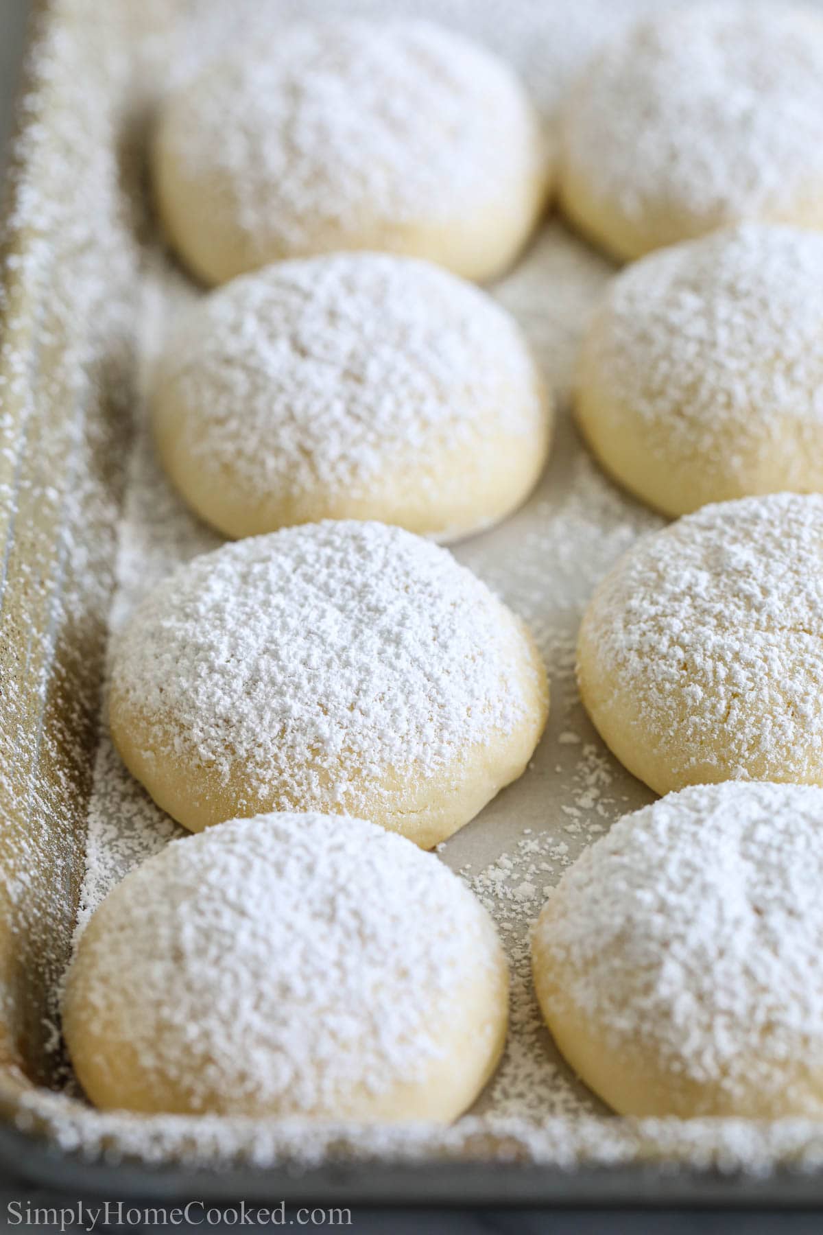 Cream Cheese Cookies covered in powdered sugar on a baking sheet.