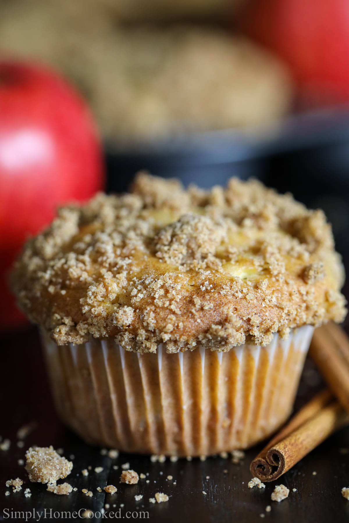 Close up of a Cinnamon Apple Muffin with cinnamon sticks nearby.