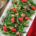 Green Bean Salad with Bacon on a white plate with tongs.