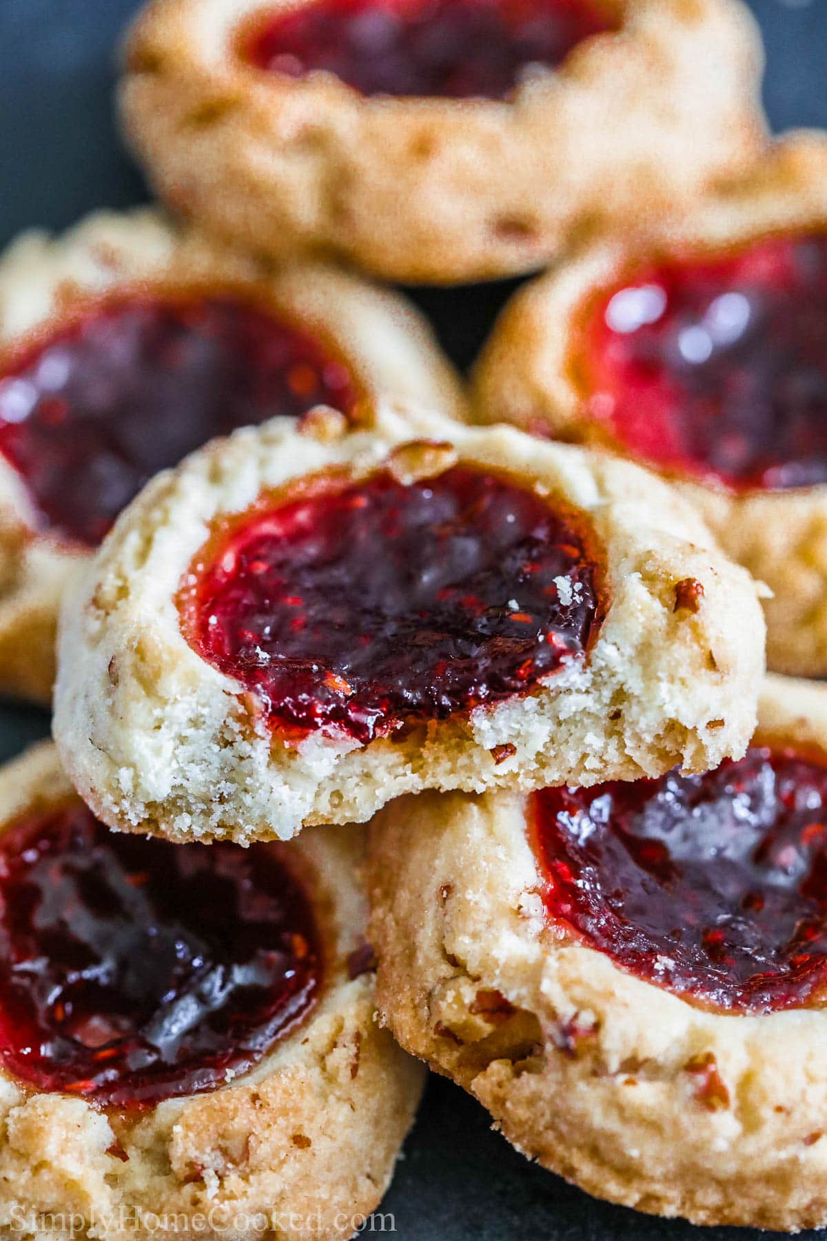 Raspberry Thumbprint Cookies in a pile with one missing a bite. 