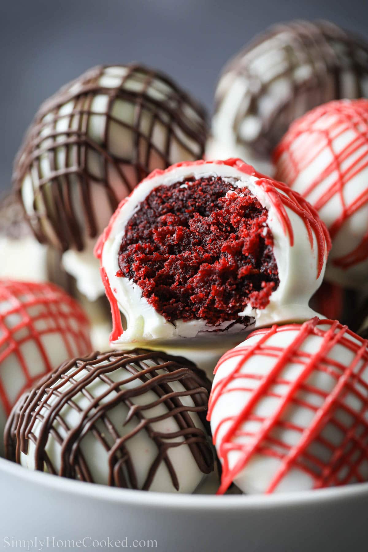 Red Velvet Cake Balls covered in white chocolate candy melt and drizzled with red and chocolate.